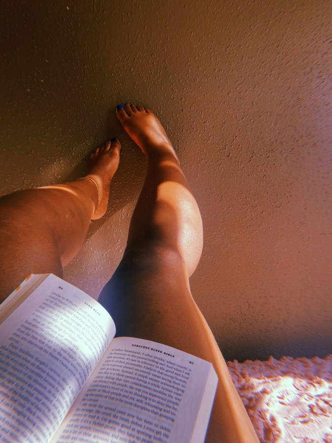 This is a photo taken from Shelli's perspective while reading a book. All you can see is the open book, her legs and feet with blue nail polish on the toes!