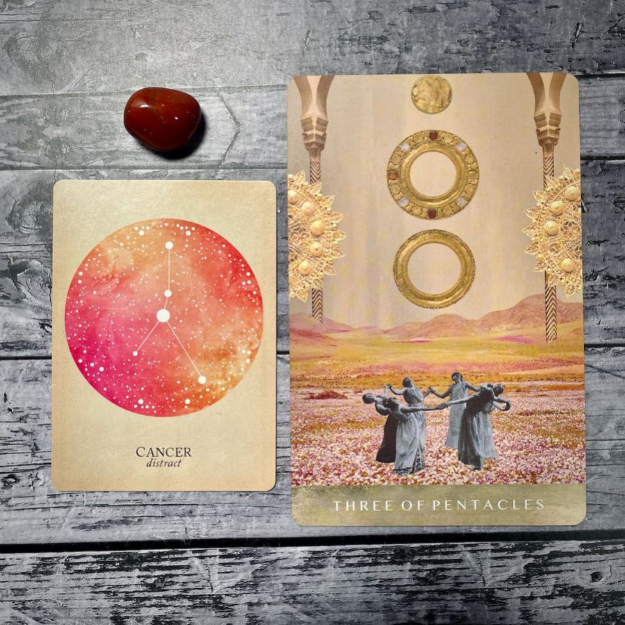 A card says cancer: distract with an sunset colored circle, next to a card that says three of pentacles with an illustration of women holding hands as they dance in a circle 