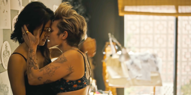 Greta kisses Katherine forcefully against the wall in the tattoo parlor's office.