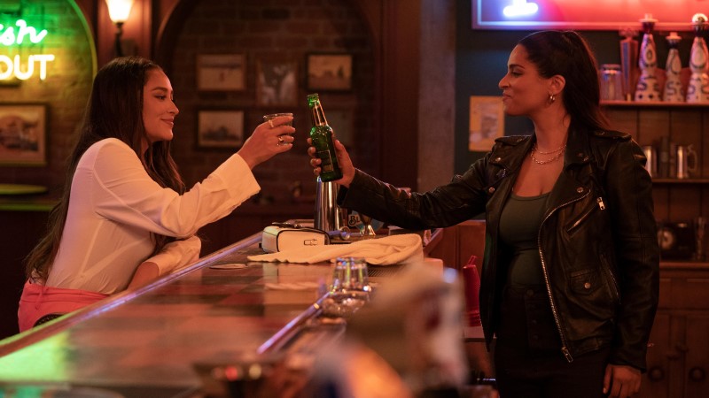 Dollface gay: Stella (Shay Mitchell) and Liv (Lilly Singh) clink glasses over a bar