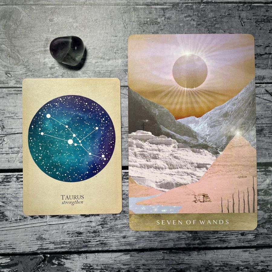 A card says taurus: strengthen with an aqua circle, next to a card that says seven of wands with an illustration of a sunrise