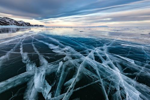 a frozen over lake with many striations where the ice is cracking