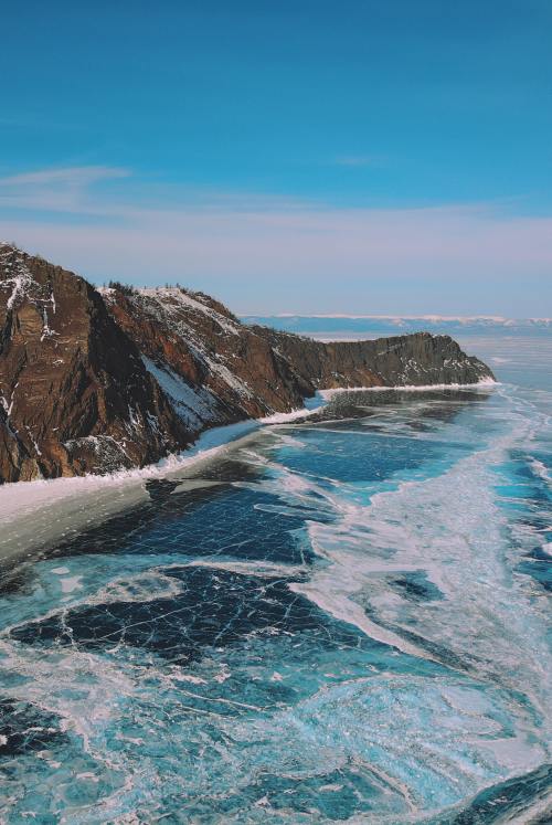 an icy lake with a large rocky protrusion in it 