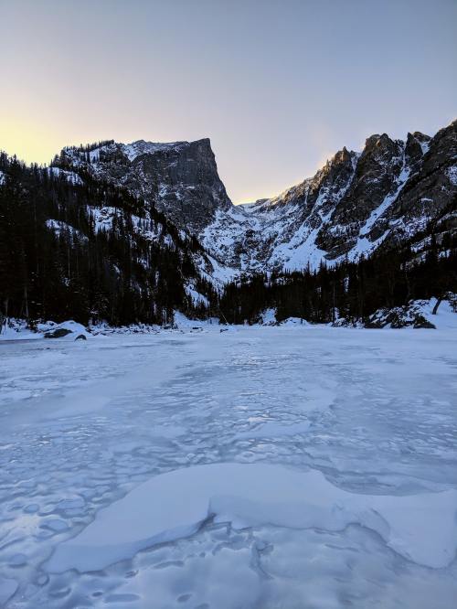 an frozen over lake full of crunchy ice with mountains in the background