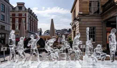 an ice sculpture of an array of people crossing a london road