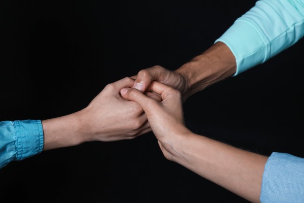 Three arms emerge out of the void, all holding hands in the middle.