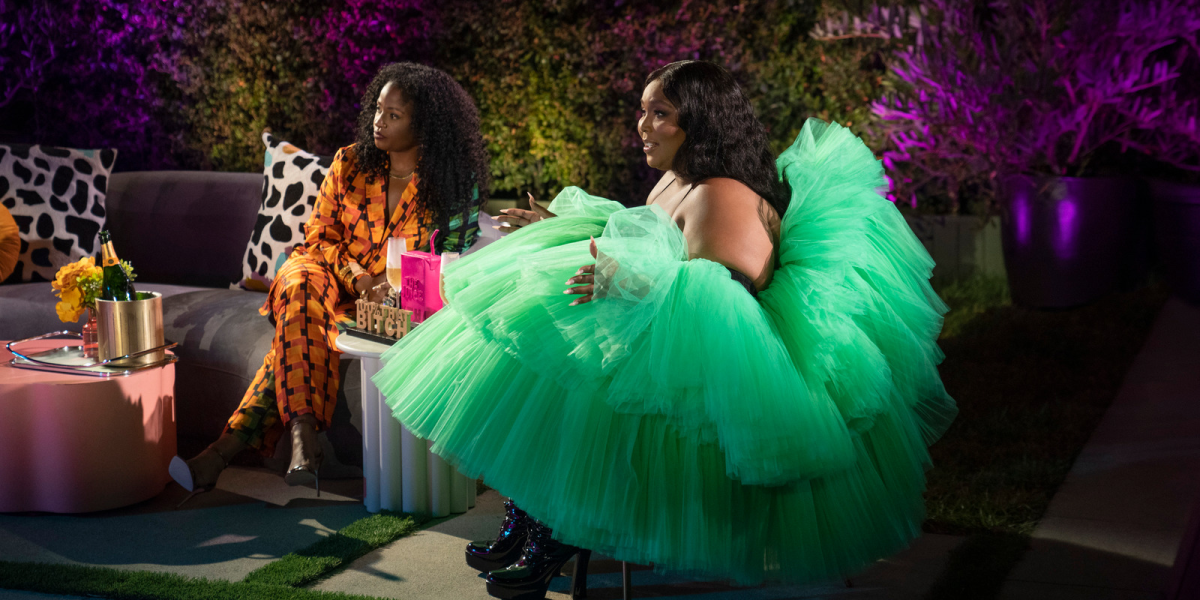 Lizzo sitting on stage in a large beautiful tulle mint green gown
