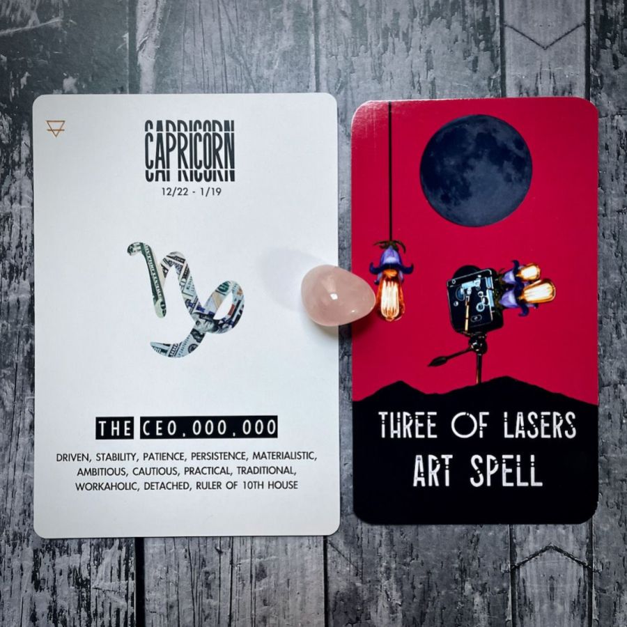 The Three of Lasers Art Spell card is bright red with a dark moon and a bright light fixture, next to it is a card that says Capricorn is The CEO