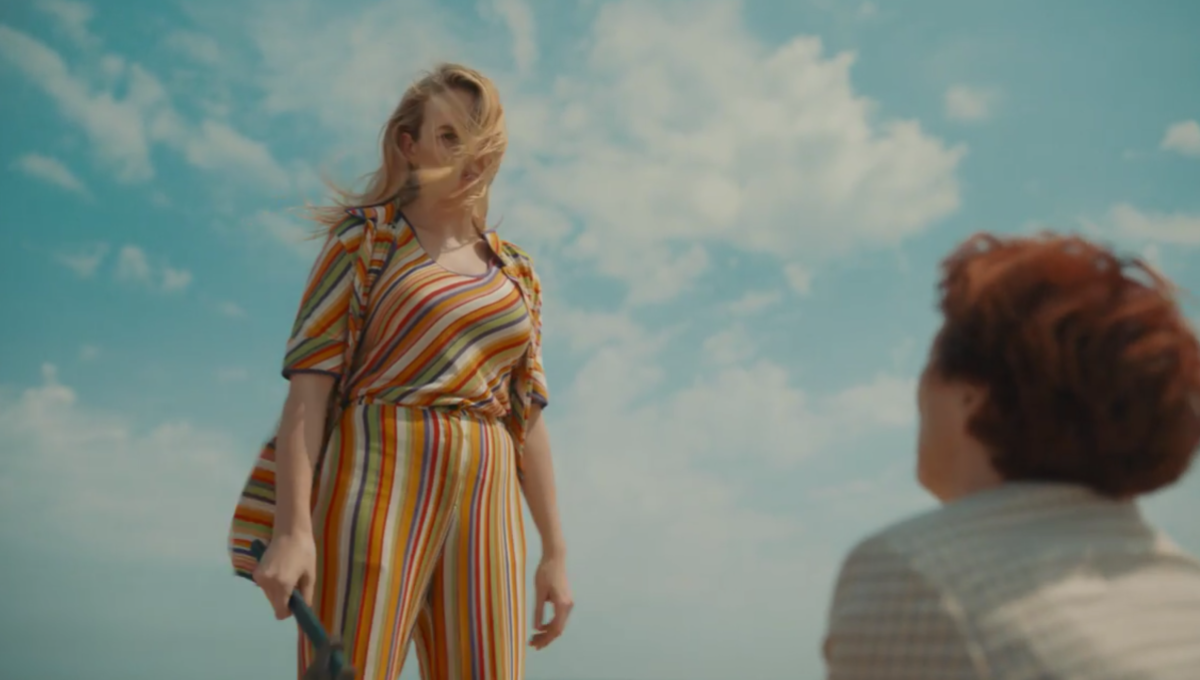 Villanelle (Jodie Comer) wears a multicolored striped leisure suit while holding a wrench