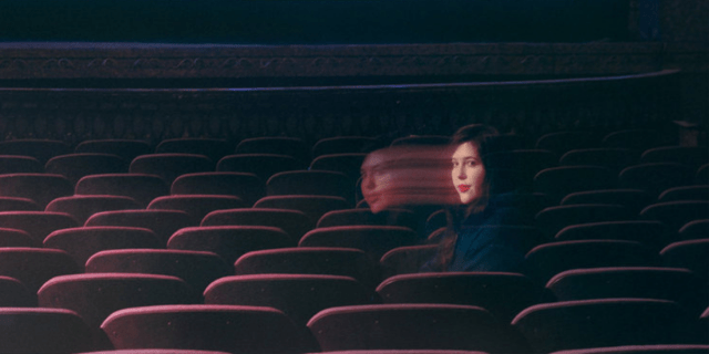 The singer Lucy Dacus sitting in an empty movie theater