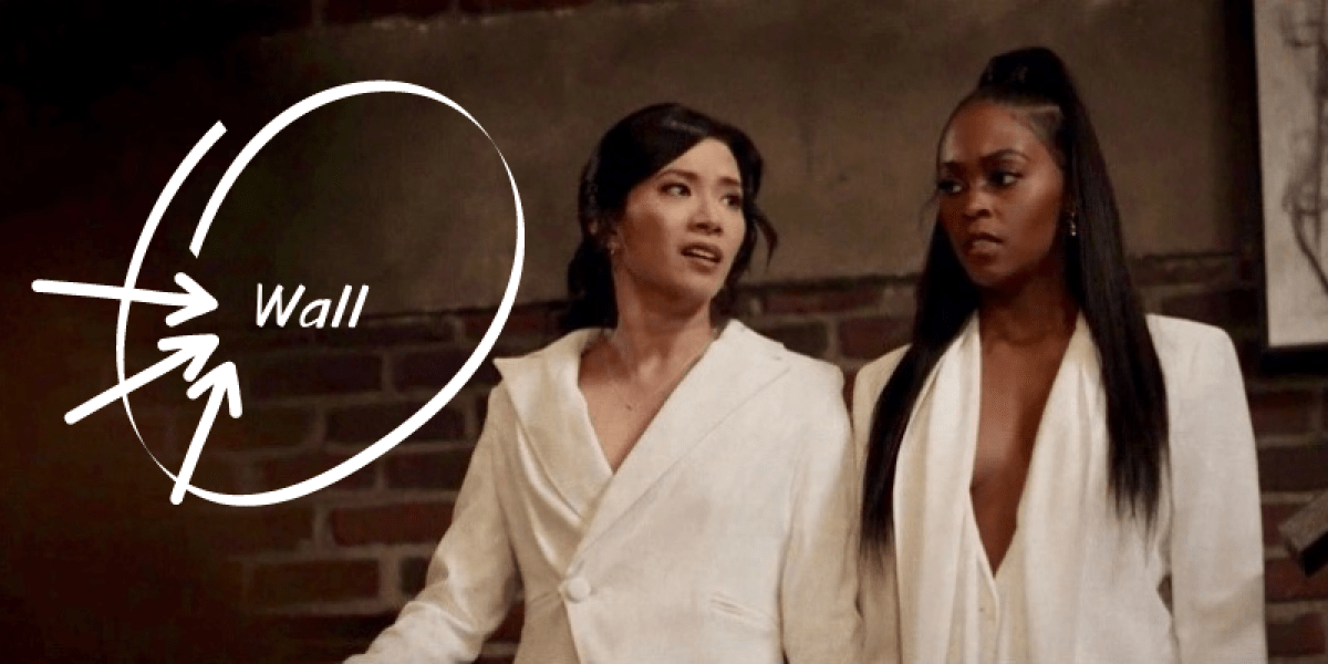 A Thundergrace image where the two characters are ready for their wedding day in complementary white suits. There is white writing that says "Wall" on the wall behind them which is then overzealously circled with arrows drawn to point toward it.