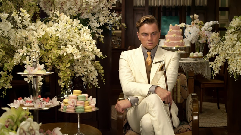 Jay Gatsby sits by a plate of food looking angry