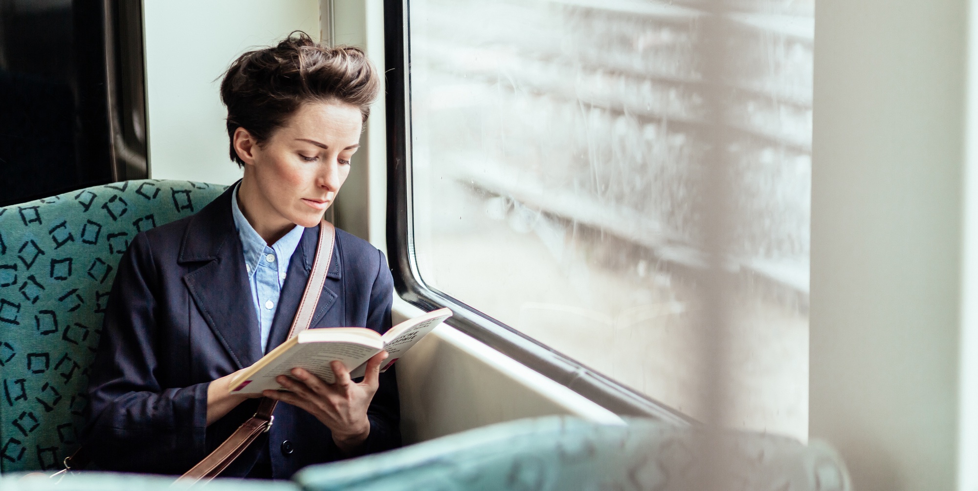 Mature businesswoman reading a book while travelling in commuter train