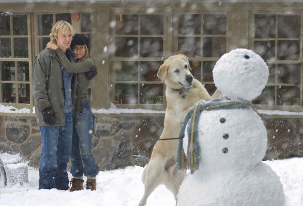 Jennifer Aniston and Owen Wilson hugging while Marley makes a snowman in Marley & Me
