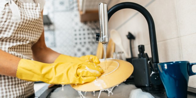 close-up of someone washing dishes in the kitchen and wearing yellow gloves