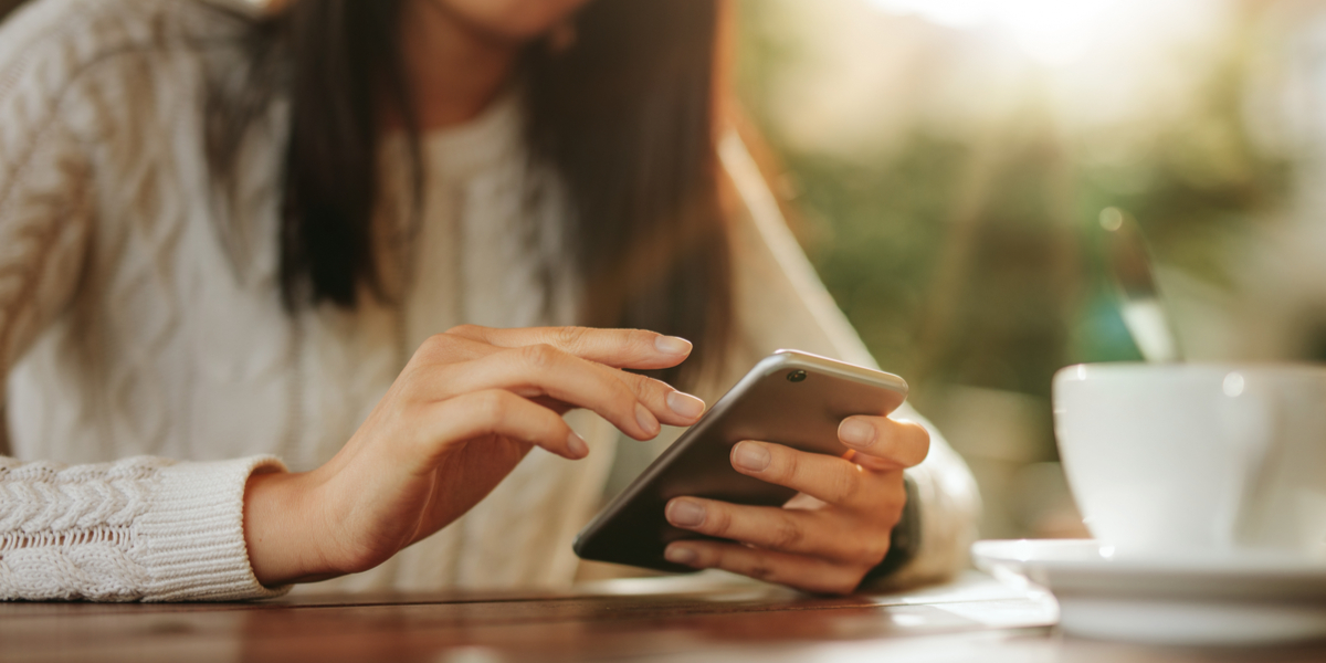 Young woman sitting at a table using mobile phone.