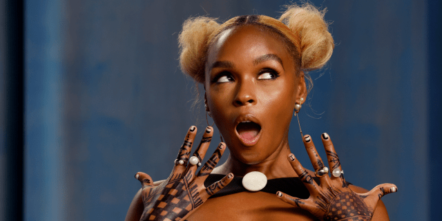 Janelle Monáe, who came out as nonbinary, with a surprised look on her face with her hairstyle in two blonde afro puffs