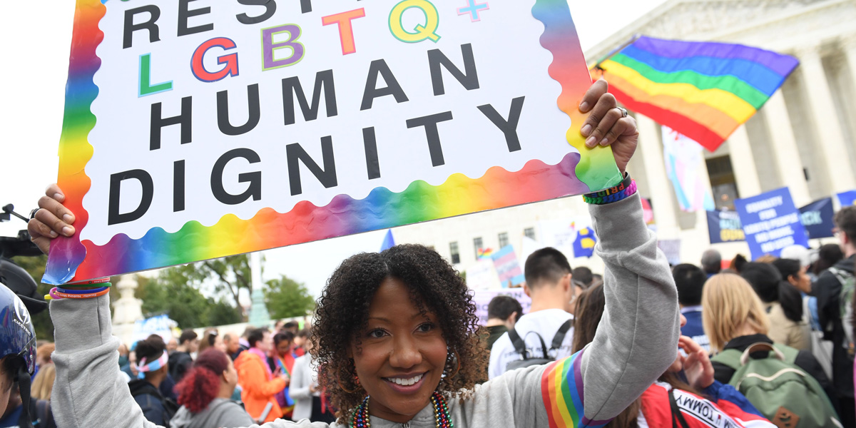 Demonstrators in favour of LGBT rights rally outside the US Supreme Court in Washington, DC, October 8, 2019, as the Court holds oral arguments in three cases dealing with workplace discrimination based on sexual orientation. A black woman holds a sign that says "Respect LGBTQ Human Dignity."