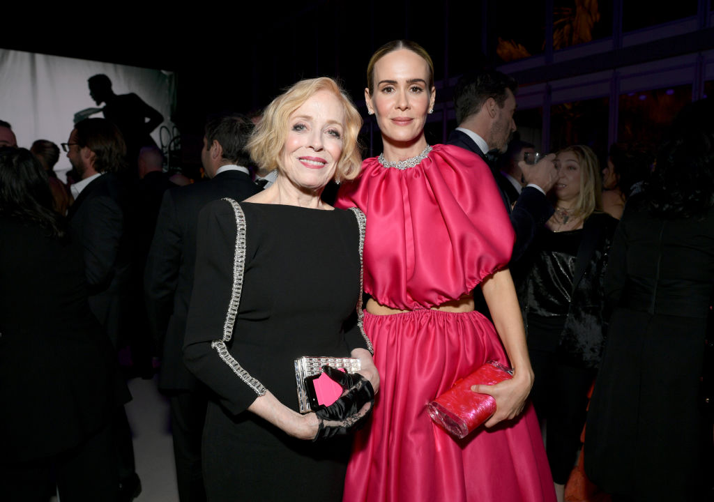 Holland Taylor and Sarah Paulson attend the 2019 Vanity Fair Oscar Party. Holland is wearing a black dress, and Sarah is wearing a pink poofy dress and holding a pink clutch.