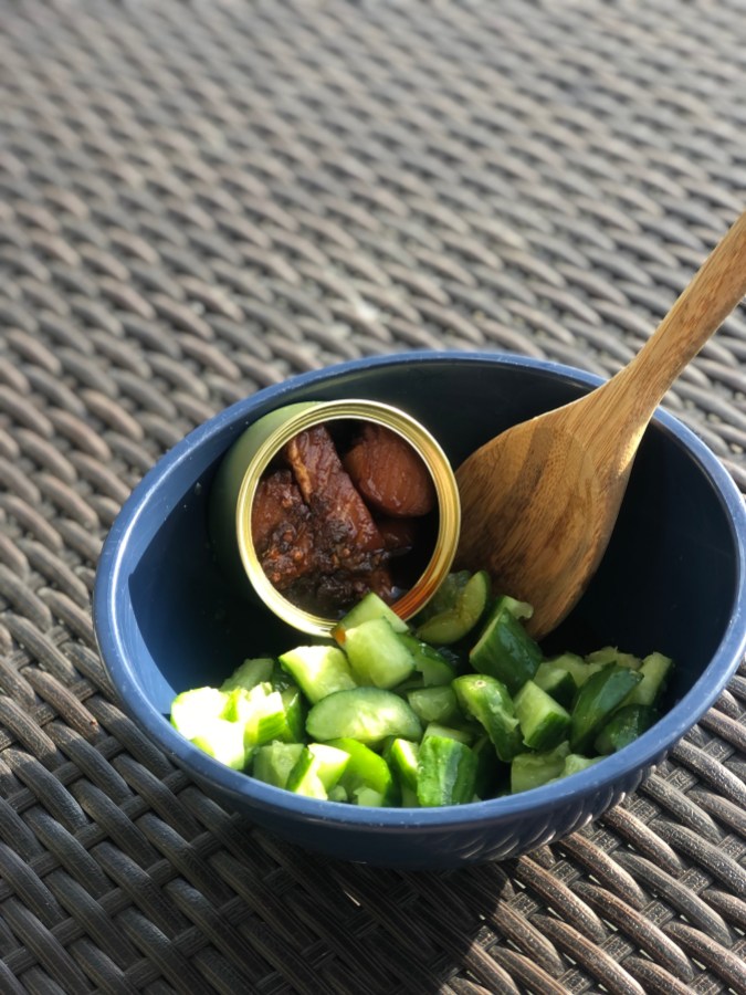 Fishwife & Fly By Jing's smoked salmon with sichuan chili crisp in a bowl with a wooden spoon and chopped cucumbers