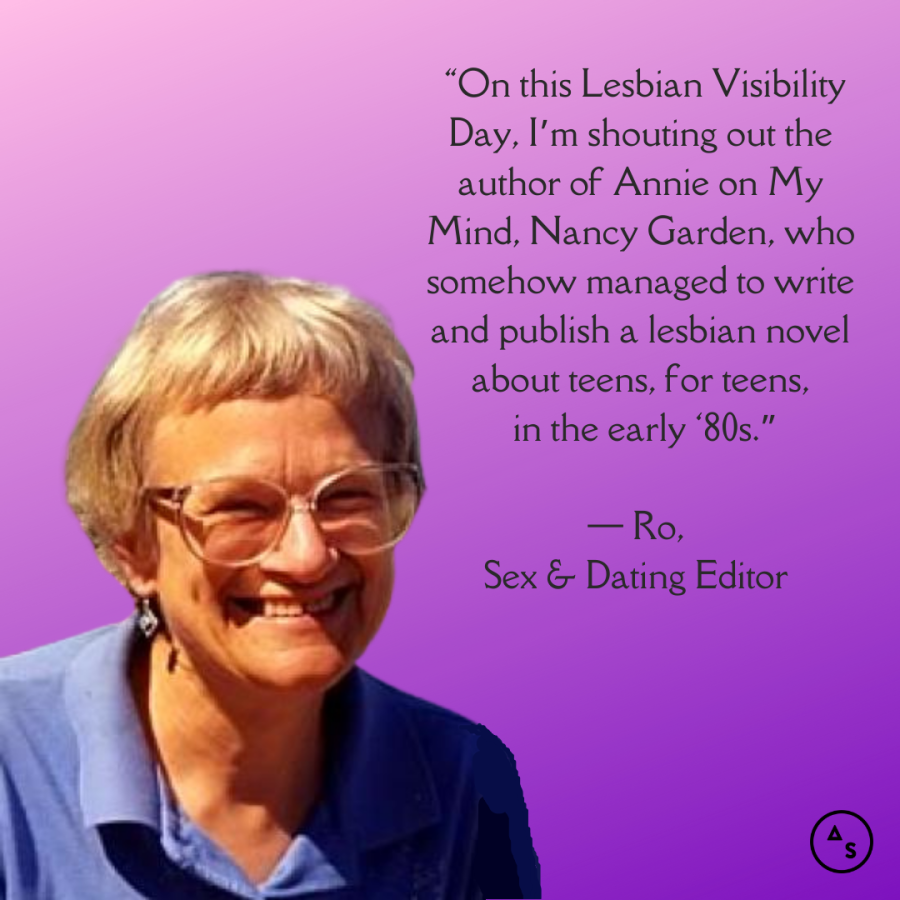 Nancy Garden is in an old photo from the 1980s, smiling in the camera. She's in front of a purple background. In front of the background is the following text: “On this Lesbian Visibility Day, I’m shouting out the author of Annie on My Mind, Nancy Garden, who somehow managed to write and publish a lesbian novel about teens, for teens, in the early ‘80s.” — Ro White, Sex and Dating Editor