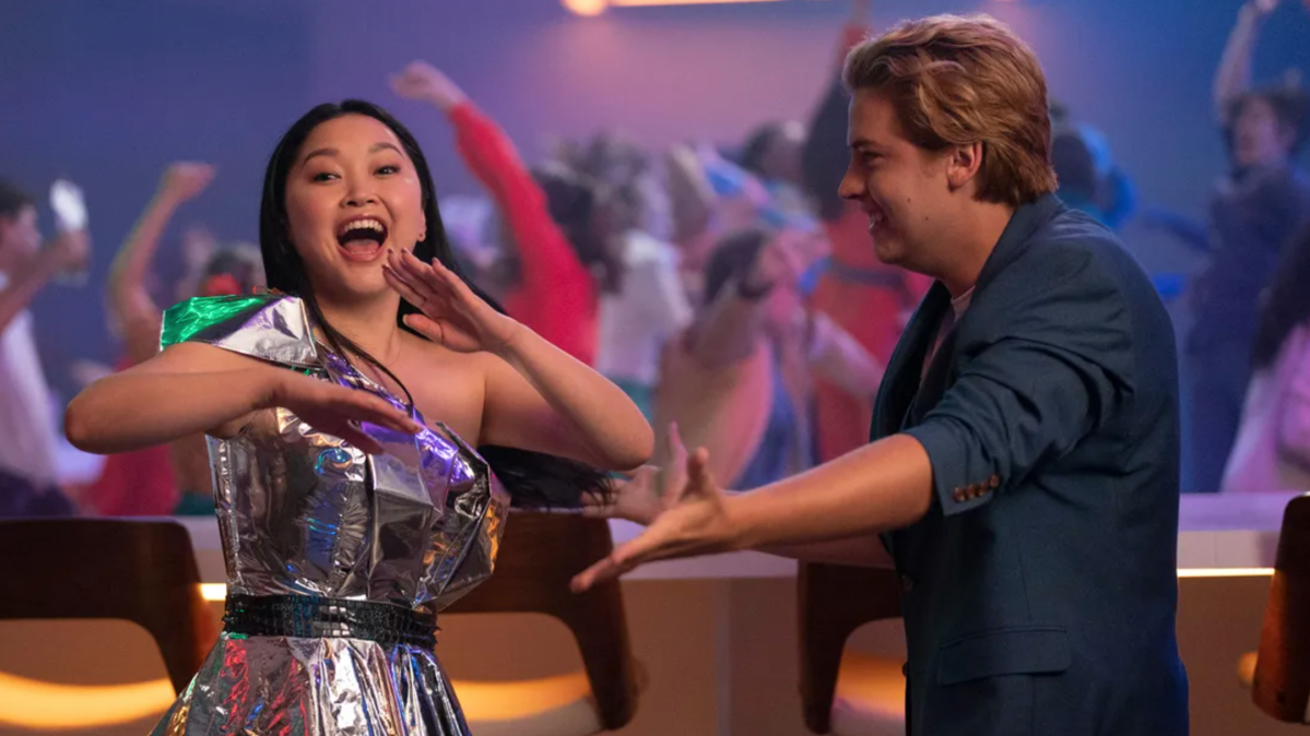 Lana Condor wears a dress that looks like tinfoil while dancing with Cole Sprouse, who is wearing a blue blazer in the movie Moonshot.