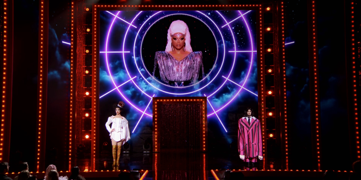 Drag Race Season 14 Finale: Lady Camden and Willow Pill stand on stage in their final lip sync looks as RuPaul's head floats above them on a big screen.