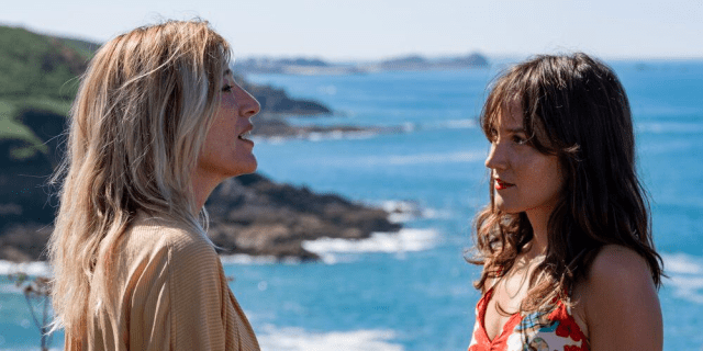 Emilie and Anaïs facing each other in front of the ocean