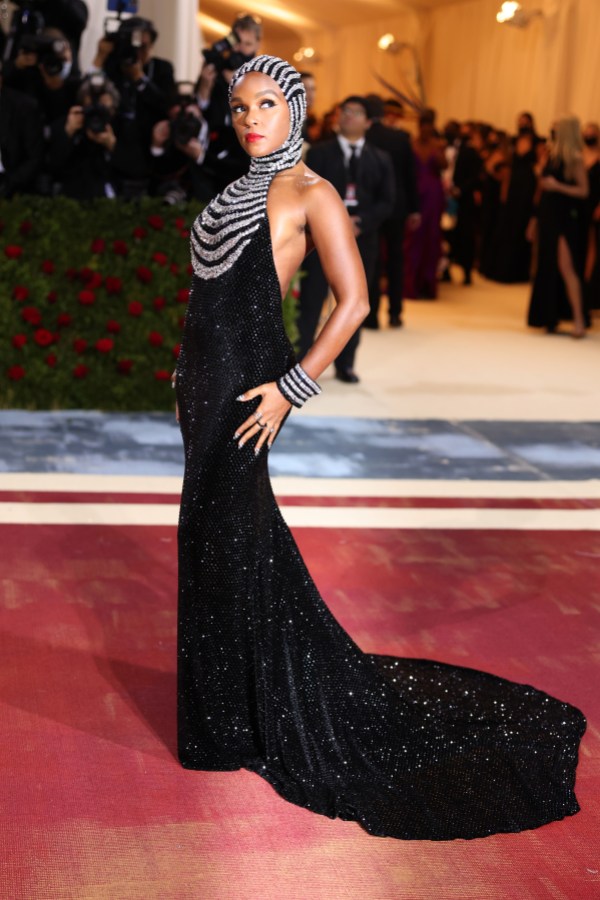 Janelle Monáe in a slender long black gown with a train and a silver chain headpiece on the red carpet
