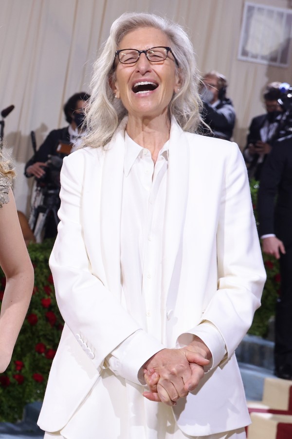 Annie Leibovitz in all white laughing at the camera.