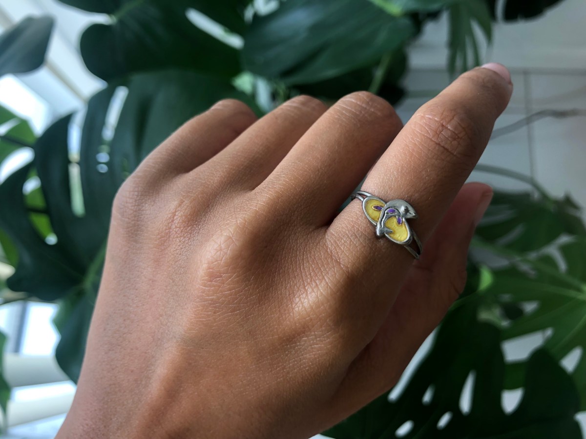 Managing Editor Kayla Kumari Upadhyaya models her yellow dolphin ring from her youth for the queer beach jewelry guide