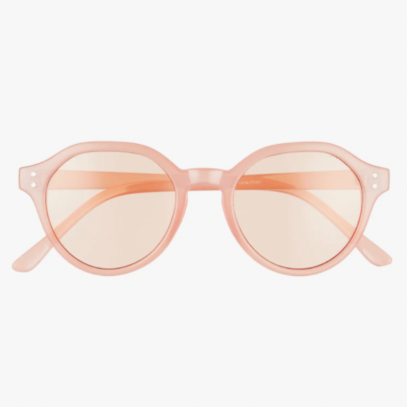 A close up of pale orange-pink round sunglasses, monotone in frame and lenses.