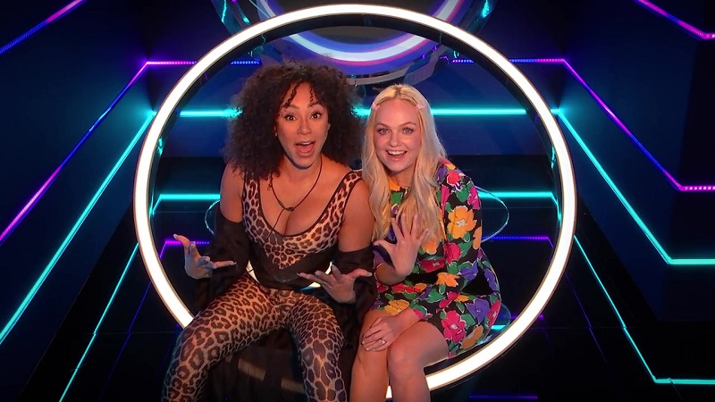 Mel B. and Emma (aka Scary Spice and Baby Spice) reveal to the other contestants that they're part of The Circle. They are sitting together, with their mouths open in shock. They are in an illuminated Circle chair.