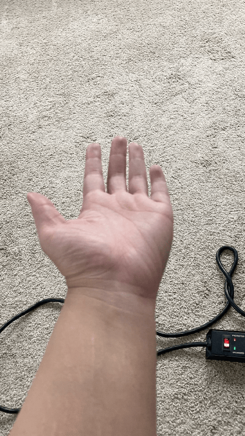 A gif shows a.Tony's open palm. They then fold in all but their pointer and middle fingers to make a "come hither" motion. A beige carpet and a black cord are in the background.