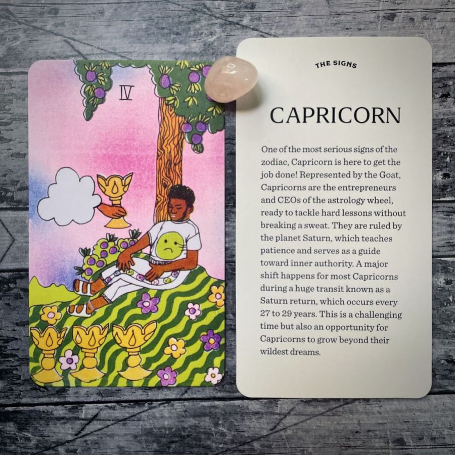 In two tarot cards on a grey background:  Left: A black man with a beard is a sleep against a tree. He has on a white shirt with a frown emoji in lime green, white pants with flower details, and white Birkenstocks. There are three gold cups on the ground in front of him. Right: Capricorn