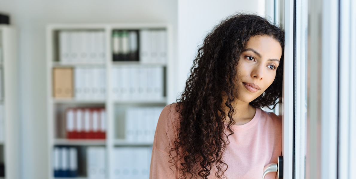 woman with curly hair stares longingly into the distance