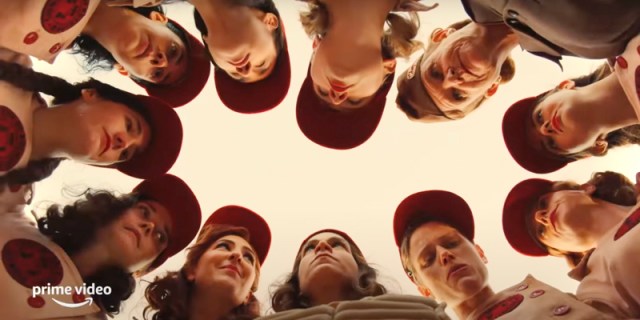 In the A League of Their Own trailer, the Rockford Peaches are all gathered together in a huddle, while the camera shoots them from below. The image is sunlight in shades of gold and red.
