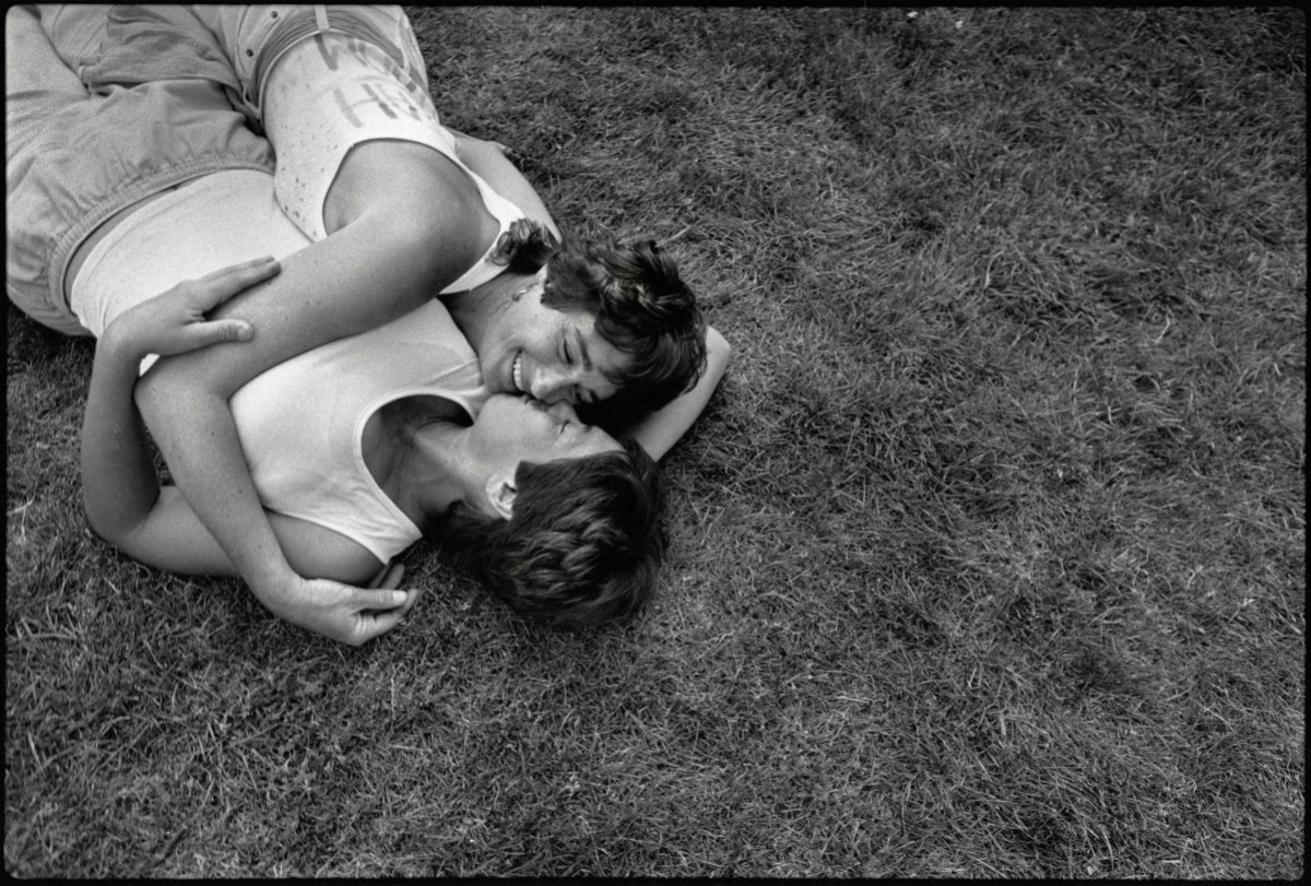 Two women (identified only as Bonnie and Laura) lie on the grass and embrace at the Civic Center d