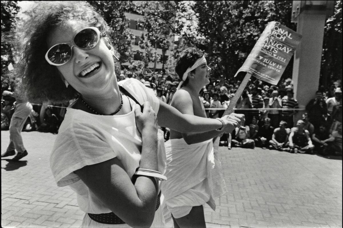 Two women smile as they hold hands and march