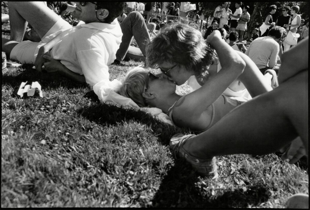 View of two women (the woman on the bottom is identified only as Regina) as they kiss one another on the grass outside the Civic Center