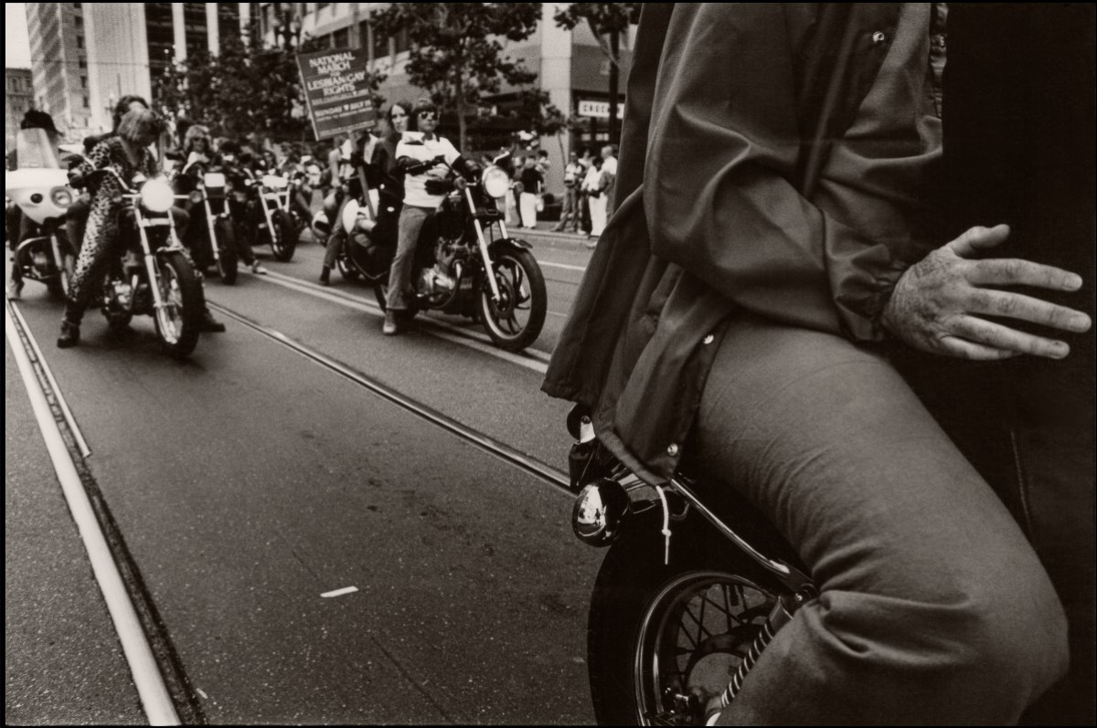 In a black and white photo, View of members of the 'Dykes on Bikes' group as they ride motorcycles along Market Street in San Francisco.