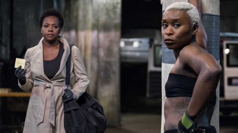 Viola Davis stands in a trenchcoat staring at Cynthia Erivo who is wearing a sports bra and boxing gloves