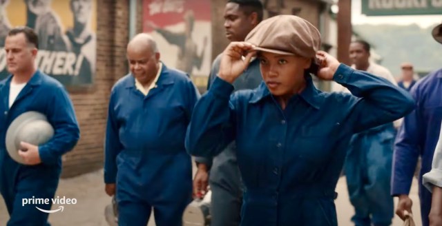 In the trailer for A League of Their Own, Chante Adams adjusts her pageboy cap and is navy blue overalls on her way to work in the factory.