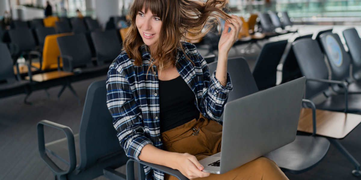 woman in airport with laptop playing with her hair