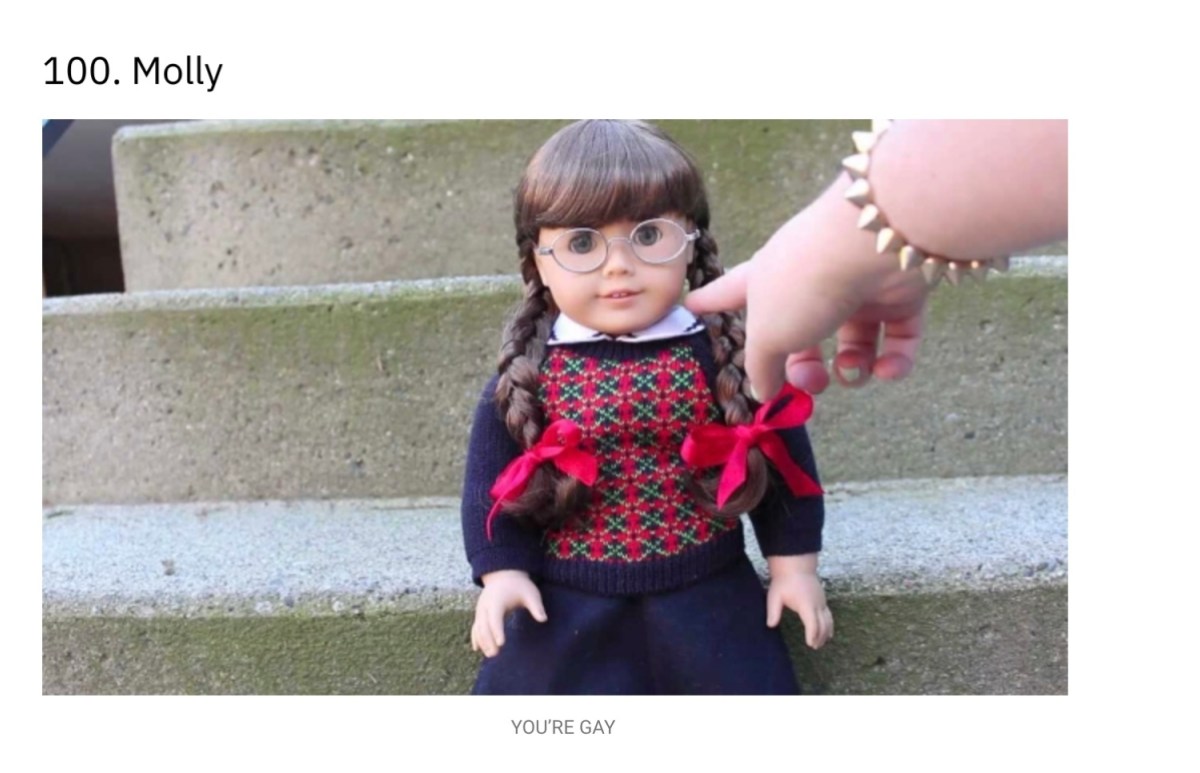 A screenshot of an Autostraddle article in which Molly the American Girl Doll is sitting on steps, a white person's hand is pointing at her. The caption underneath reads "You're Gay!"