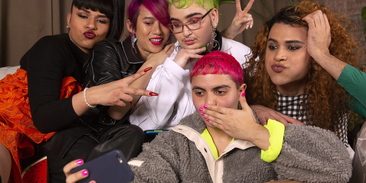 A group of friends of varying genders taking group selfie.