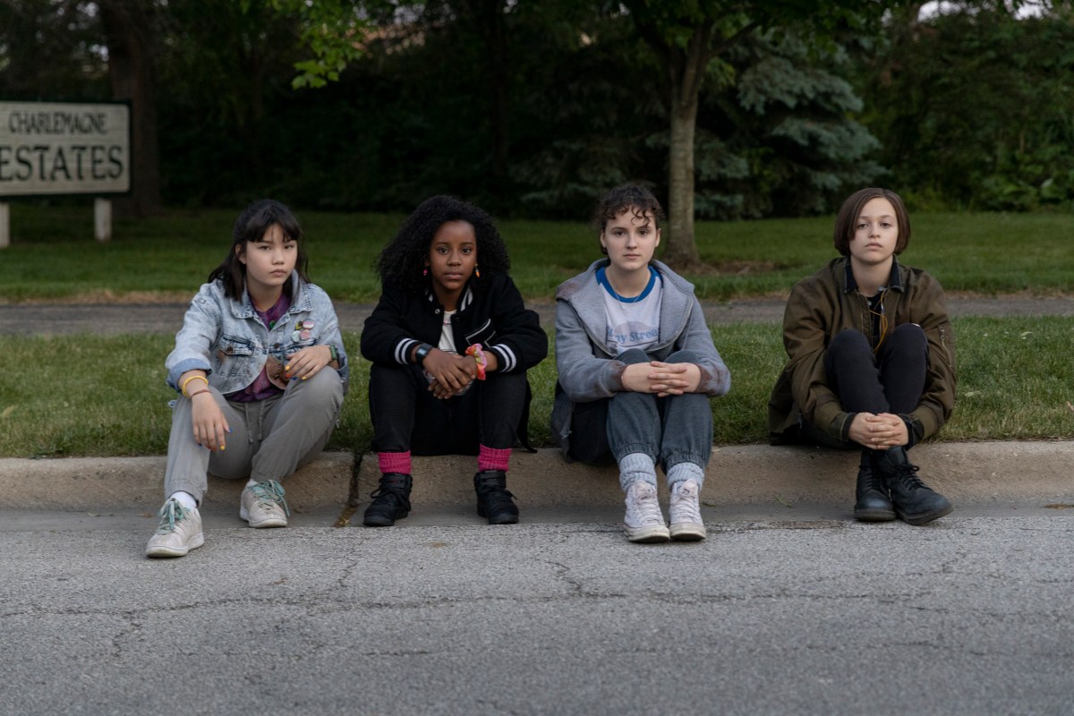 4 teen girls sit on a curb and stare into the camera