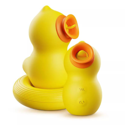 Two yellow silicone sex toys shaped like the body of a duck are against a white background. One faces to the right and a smaller one faces to the front. The duck's "beaks" are open, orange circles. Inside each beak, there is a yellow "tongue."