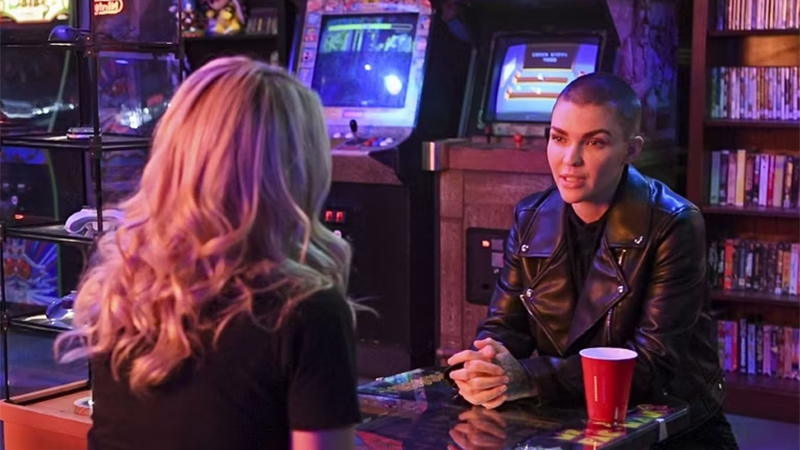 Ruby Rose in a leather jacket in their game room, talking to V