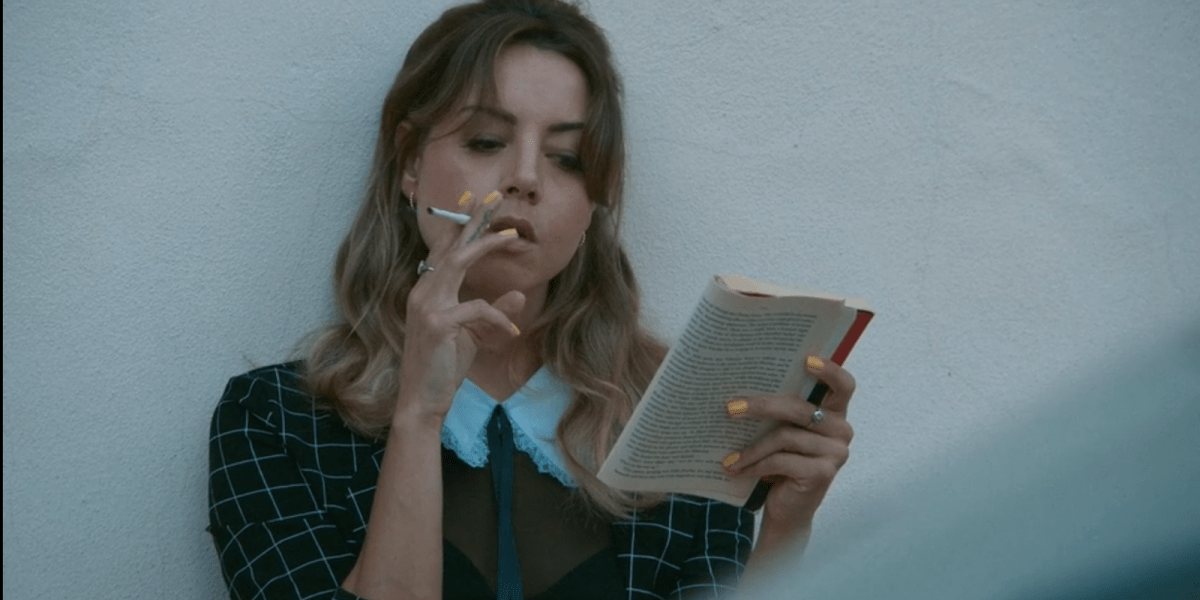 Aubrey Plaza smoking a cigarette and reading